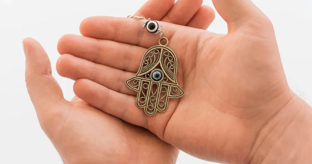 Gold Hamsa hand of Fatima pendant with blue gemstone